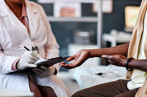A man with darker skin tone getting screened by a dermatologist for possible skin cancer